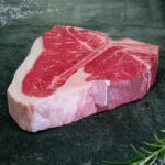 Creekstone Farms US Porterhouse Steak mit großem Filet-Anteil für Gezer Gastro-Kunden, präsentiert auf Schieferplatte.