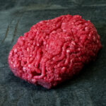 Rohes Hackfleisch Creekstone Farms USA auf einer schwarzen Schieferplatte.