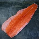 Ein ganzes rohes Lachsfilet aus Norwegen auf einer schwarzen Schieferplatte für Gezer Kunden aus der Gastronomie.