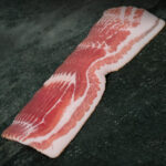 Aromatischer regionaler Bacon vom Duroc-Schwein auf Schieferplatte für Gezer Gastronomie-Kunden.