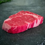 Rohes Ribeye Steak der Färse aus Pommern auf schwarzer Schieferplatte von Gezer Fleischmanufaktur GmbH.