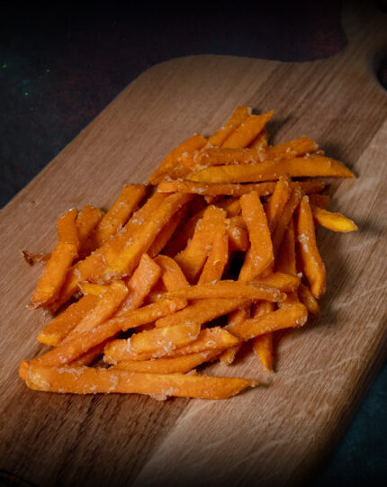 Süßkartoffel-Pommes, leuchtend orange auf einer Schieferplatte präsentiert für Gezer Kunden.