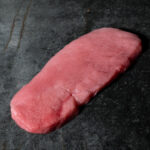 Schnitzel vom regionalen Duroc-Schwein, fachgerecht zugeschnitten auf einer Schieferplatte präsentiert für Gezer Kunden.