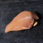 Kikok Hähnchenbrust vom Maishähnchen, mit charakteristischer goldgelber Farbe auf einer Schieferplatte präsentiert für Gezer Gastro-Kunden.