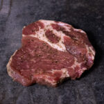 Duroc Schweinenackensteak mit Kräutermarinade, hochwertig präsentiert auf einer Schieferplatte für Gezer Kunden.