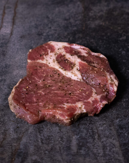 Duroc Schweinenackensteak mit Kräutermarinade, hochwertig präsentiert auf einer Schieferplatte für Gezer Kunden.