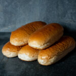 BEKABUN® Hot Dog Buns, frisch präsentiert auf einer Schieferplatte für Gezer Gastro-Kunden.