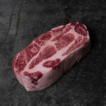 Rohes Nackensteak vom Iberico-Schwein, reich marmoriert auf einer Schieferplatte präsentiert für Gezer Kunden.