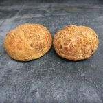 SweetGold Süßkartoffel Burger Buns, goldgelb glänzend auf einer Schieferplatte präsentiert für Gezer Kunden.