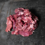 Wildschweingulasch, ungewürzte und handgeschnittene Fleischwürfel auf einer Schieferplatte präsentiert für Gezer Kunden.