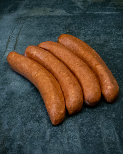 Original Käsekrainer aus Österreich, goldbraun auf einer Schieferplatte präsentiert für Gezer Kunden.